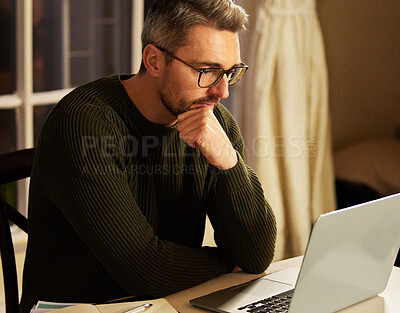 Buy stock photo Cropped shot of a handsome mature businessman looking thoughtful while working on his laptop at home