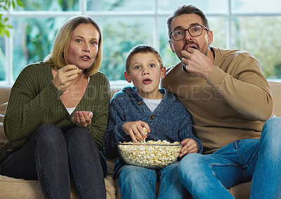 Buy stock photo Shot of a family enjoying a bowl of popcorn while watching a movie