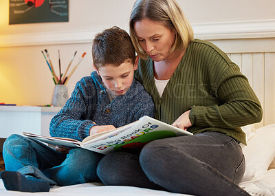 Buy stock photo Shot of a mother and son reading a book about dinosaurs together in a bedroom at home