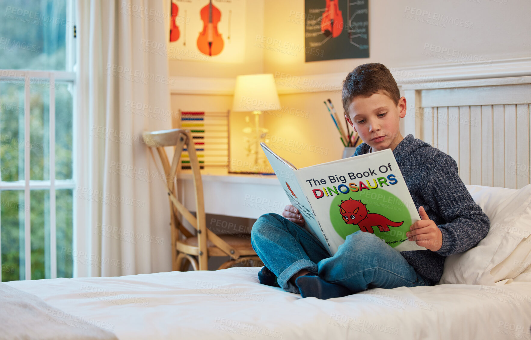 Buy stock photo Relax, reading and child with books in bed for learning, education and language development. Home, curiosity and young boy with bedtime story for fantasy, dinosaur history and knowledge in bedroom