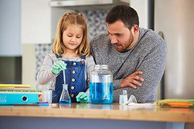 Buy stock photo Shot of a little girl completing scientific experiments with her dad at home