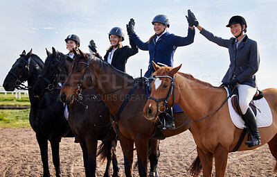 Buy stock photo Cropped shot of a group of attractive young female jockeys high-fiving while sitting on their horses' backs