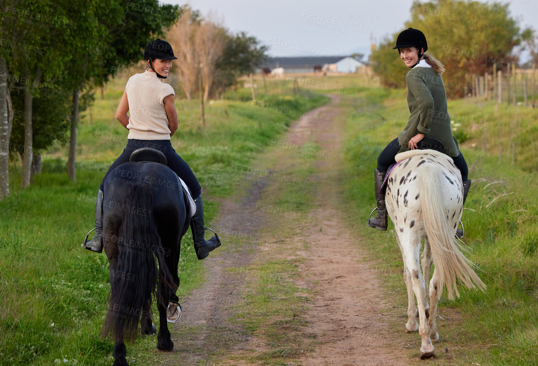 Buy stock photo Shot of two young women riding their horses outside on a field