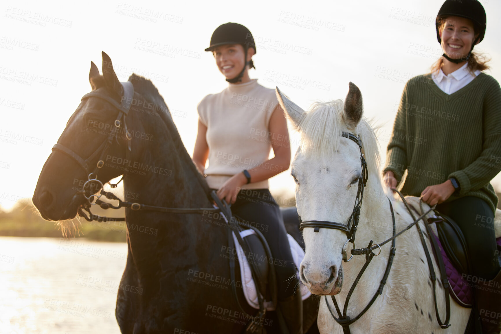 Buy stock photo Shot of two young women riding their horses outside on a field
