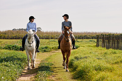 Buy stock photo Full length shot of two young woman riding their horses on the ranch