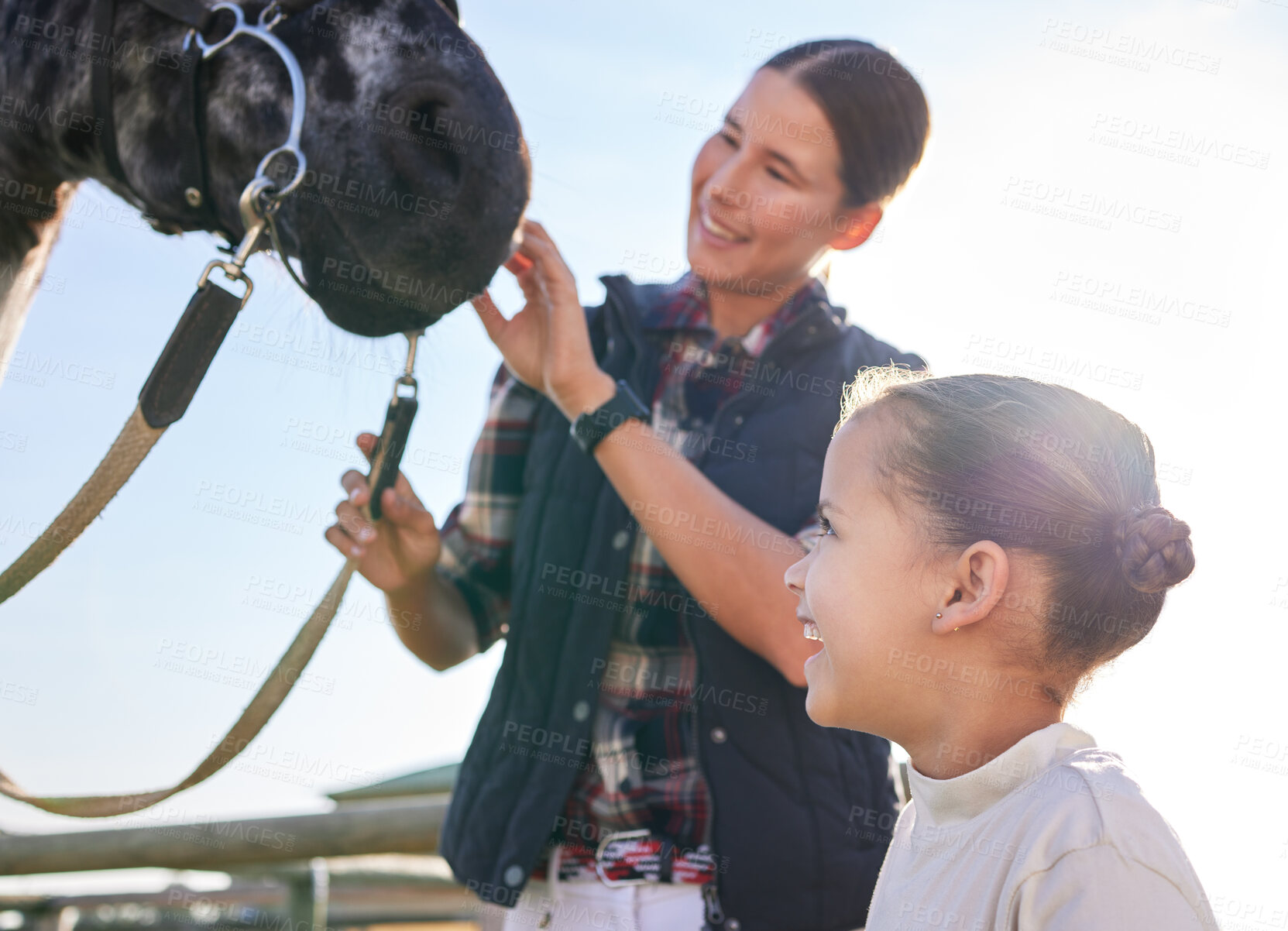 Buy stock photo Cropped shot of an attractive young woman and her daughter petting a horse outside on the ranch