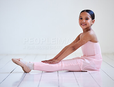 Buy stock photo Portrait of a little girl stretching her legs in a ballet studio
