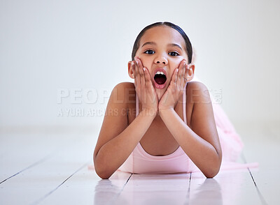 Buy stock photo Portrait of a little girl looking surprised while lying on the floor in a ballet studio