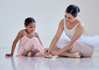 Buy stock photo Shot of a teacher helping her student put on ballet shoes in a dance studio