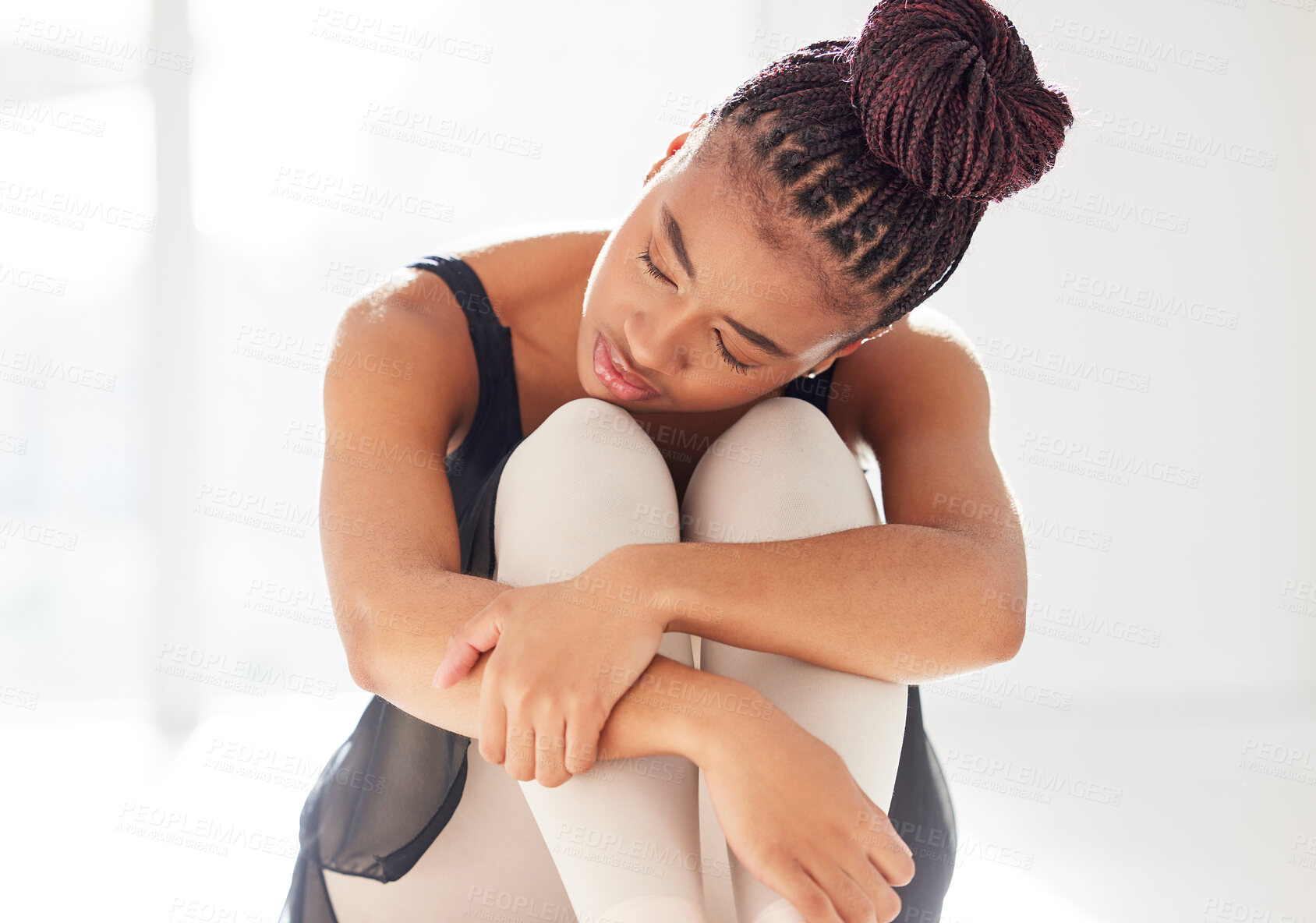 Buy stock photo Shot of a ballerina looking sad while sitting in her dance studio
