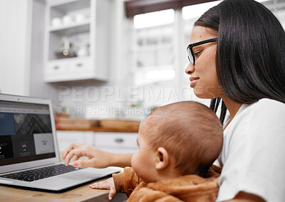 Buy stock photo Shot of a young mother using a laptop while holding her son at home