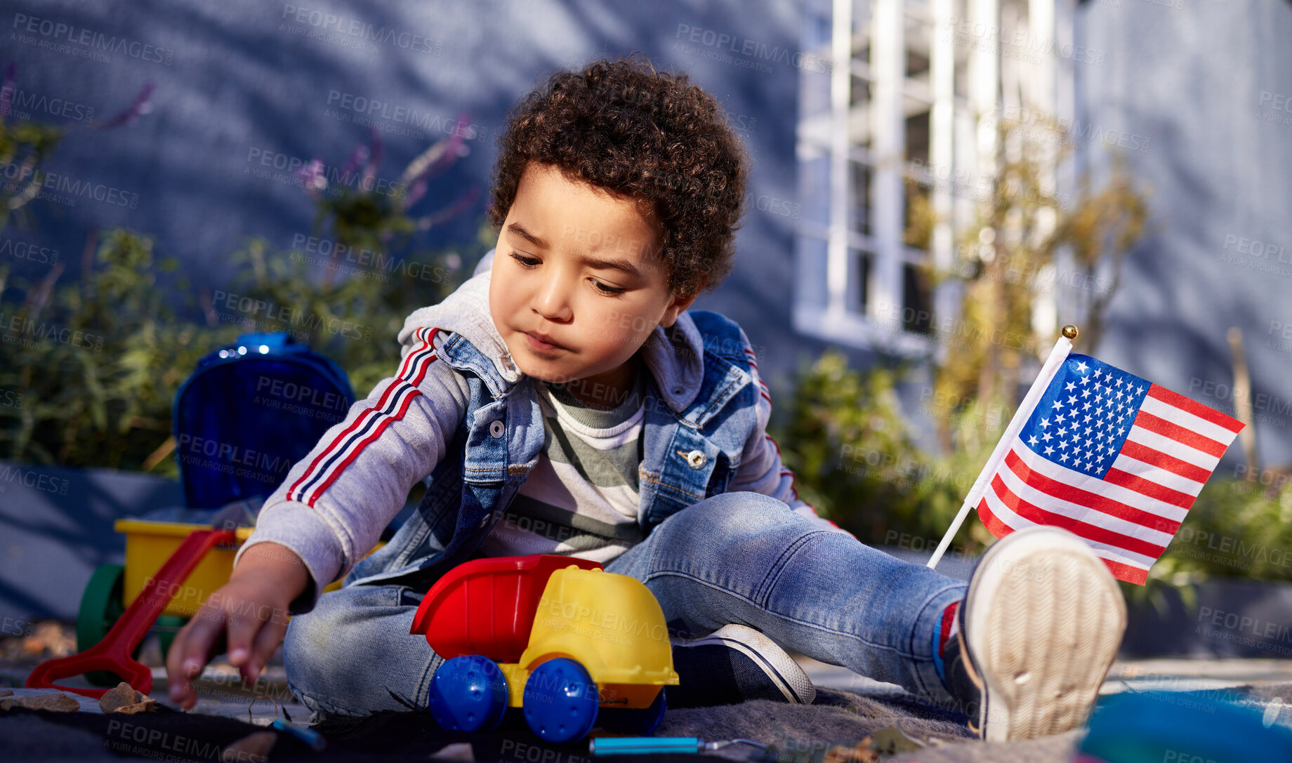 Buy stock photo Shot of an adorable little boy playing with his toys outdoors