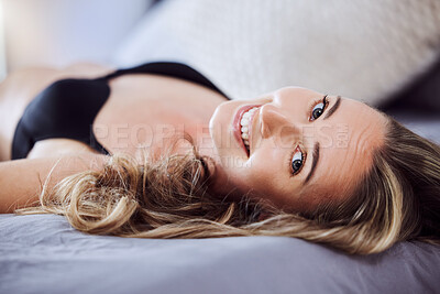Buy stock photo Shot of an attractive young woman wearing lingerie and relaxing on the bed at home