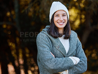 Buy stock photo Shot of an attractive young woman standing alone outside with her arms folded