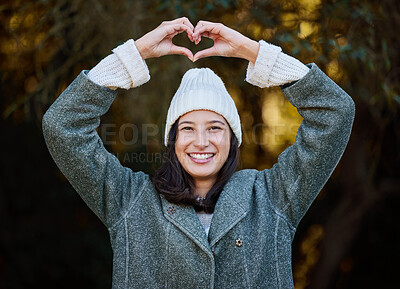 Buy stock photo Shot of an attractive young woman standing alone outside and making a heart-shaped gesture