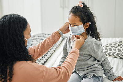 Buy stock photo Shot of a young mother and daughter putting on masks at home