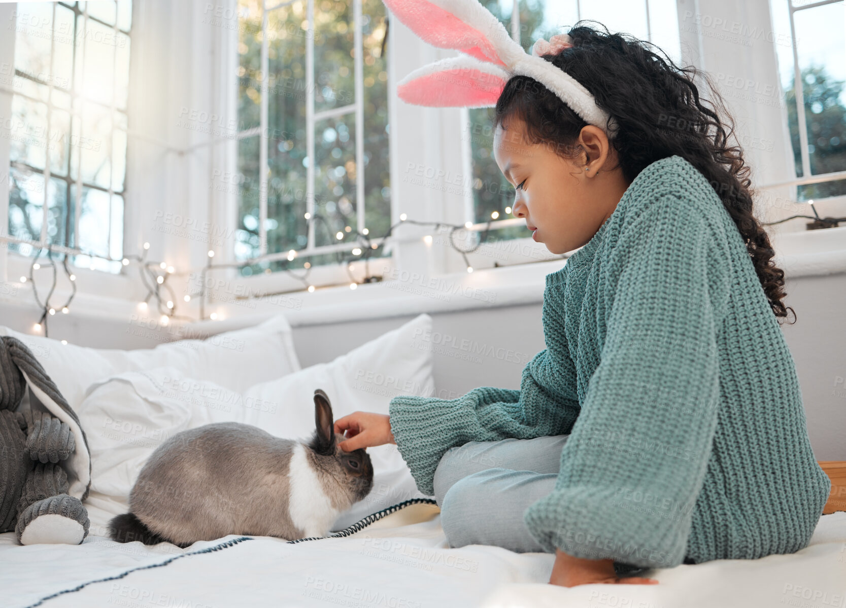 Buy stock photo Shot of an adorable little girl sitting on her bed and bonding with her pet rabbit at home
