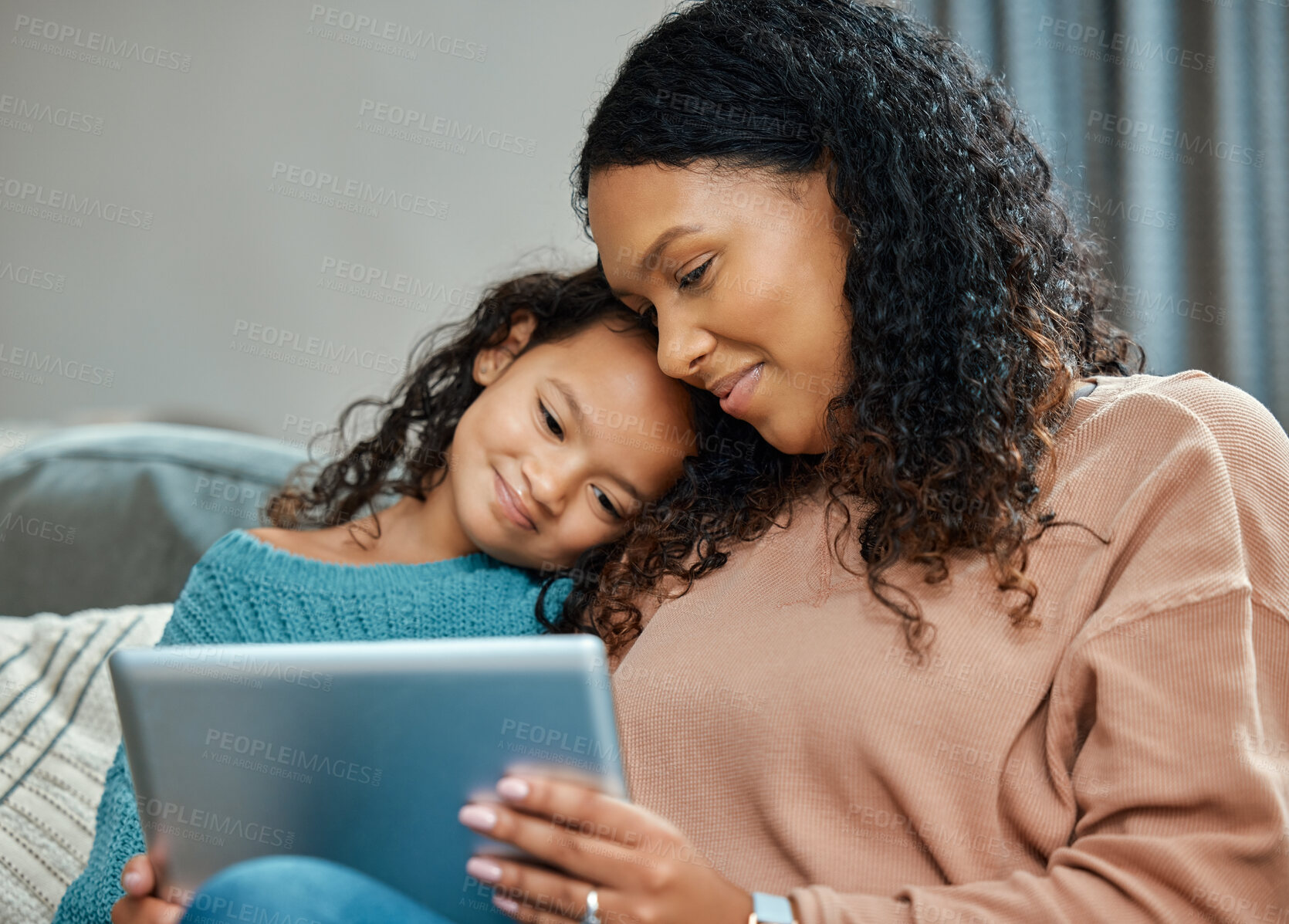 Buy stock photo Shot of an attractive young woman sitting and bonding with her daughter while using a digital tablet