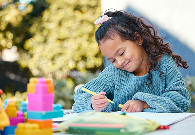 Buy stock photo Shot of a little girl completing homework in her yard