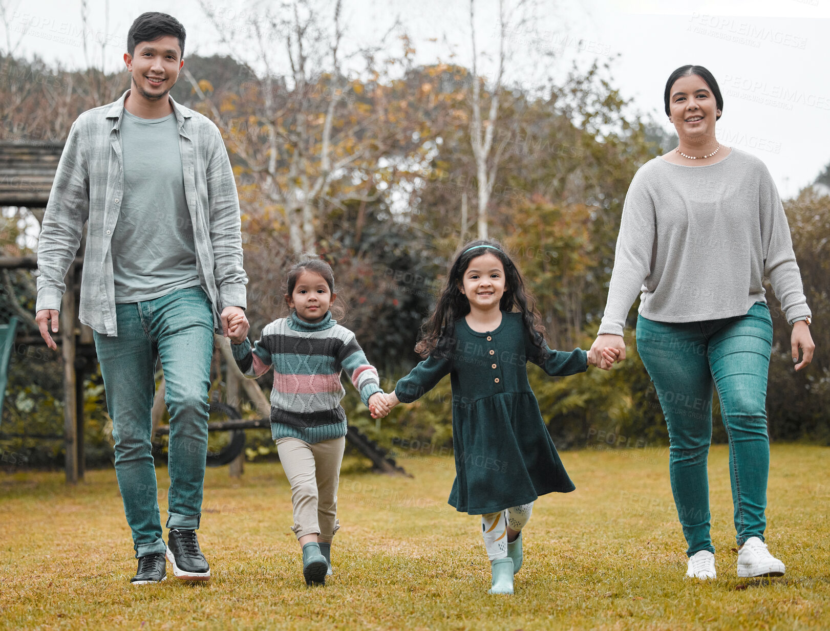 Buy stock photo Full length shot of a young family holding hands and walking through the park