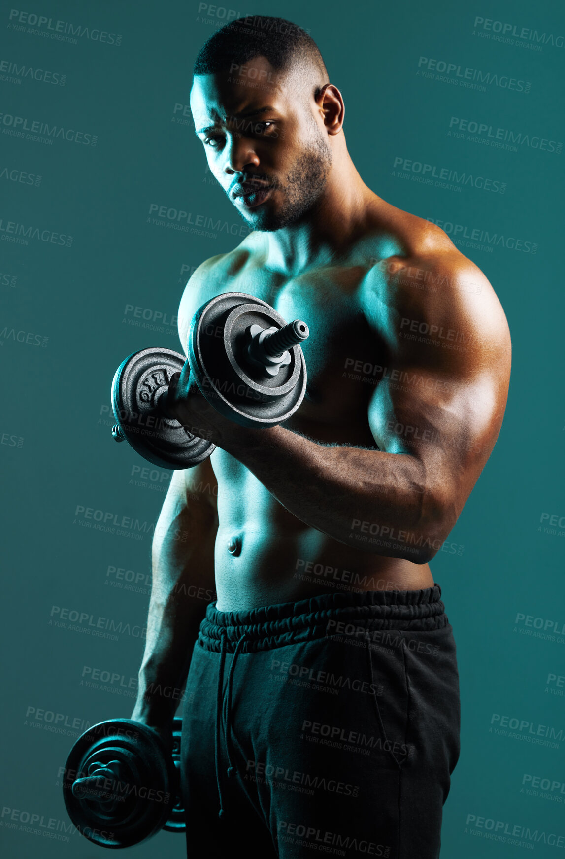 Buy stock photo Shot of a handsome young man lifting weights against a studio background
