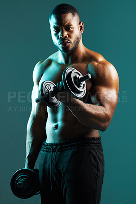 Buy stock photo Shot of a handsome young man lifting weights against a studio background