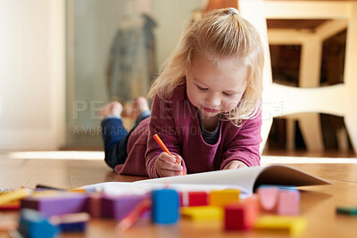Buy stock photo Shot of a little girl lying on the floor with her colouring book