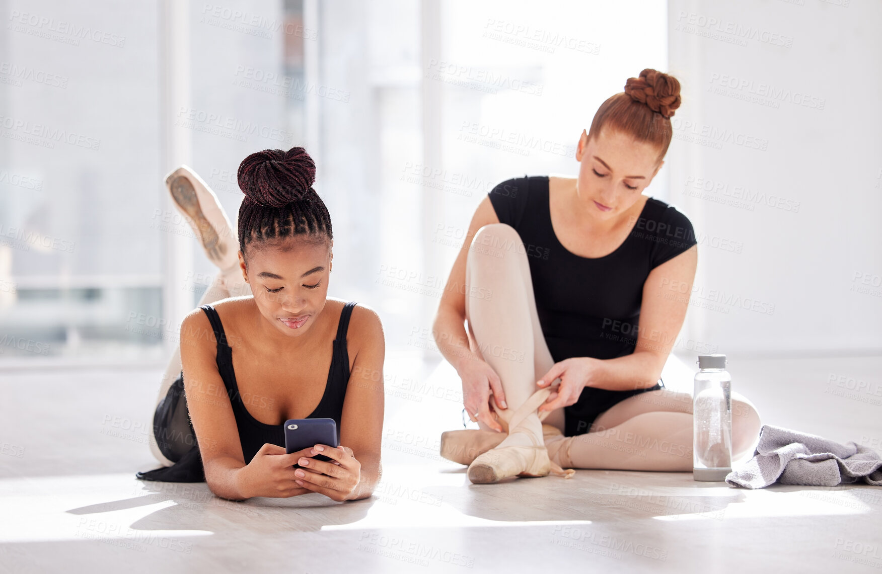 Buy stock photo Shot of two ballet dancers taking a break while using a smartphone