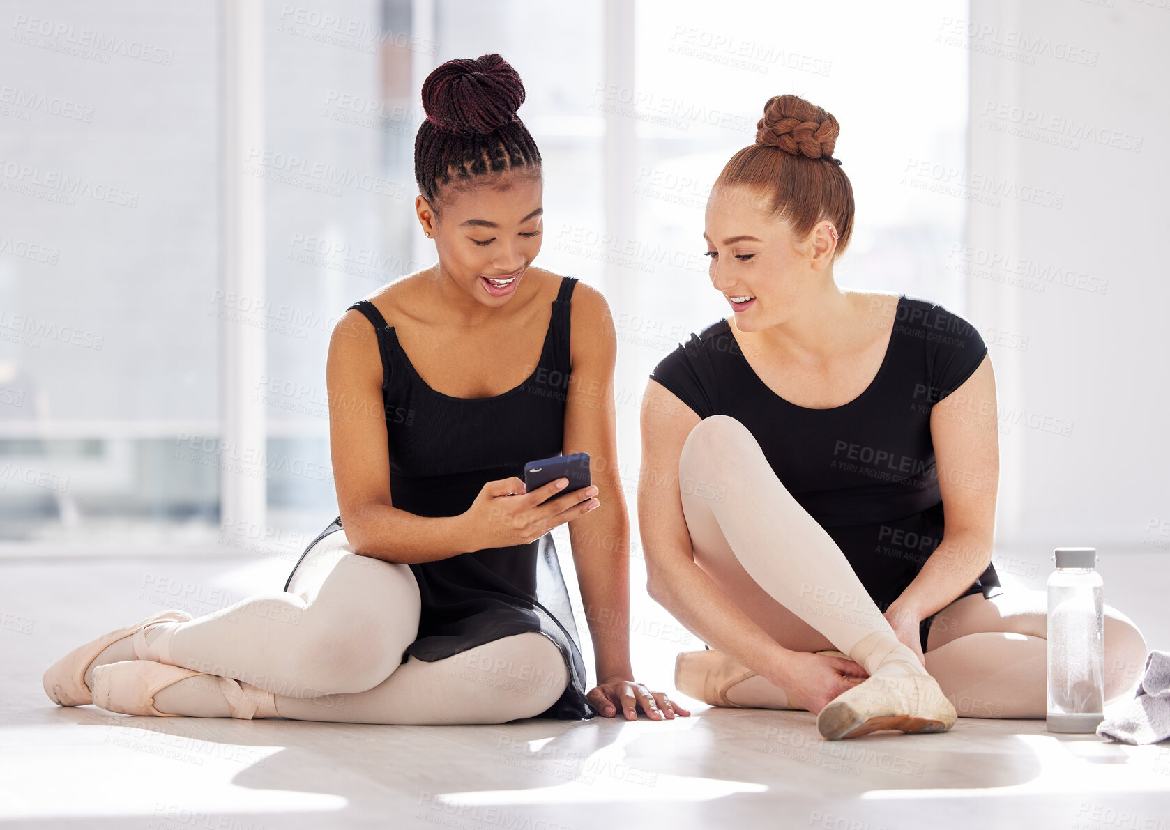 Buy stock photo Shot of a ballet dancer showing her friend her smartphone