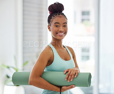 Buy stock photo Shot of an attractive young woman standing alone and holding a yoga mat in a studio