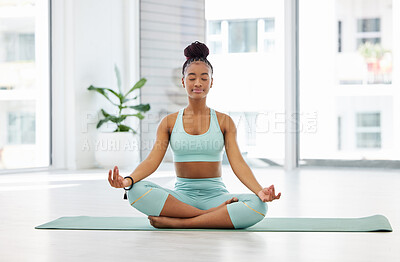 Buy stock photo Full length shot of an attractive young woman sitting alone with her legs crossed and meditating in the studio