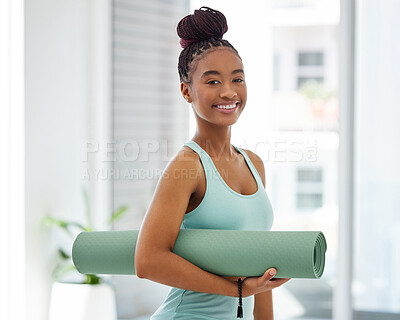 Buy stock photo Shot of an attractive young woman standing alone and holding a yoga mat in a studio