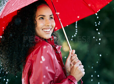 Buy stock photo Shot of a beautiful young woman standing in the rain with an umbrella