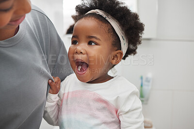 Buy stock photo Shot of an adorable little girl opening her mouth to show her teeth to her mother in the bathroom at home