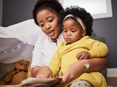 Buy stock photo Shot of a young mother and daughter reading a book at home