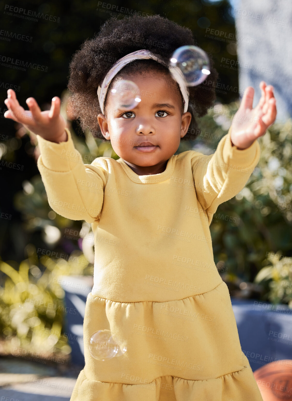 Buy stock photo Shot of a little girl catching bubbles in a garden