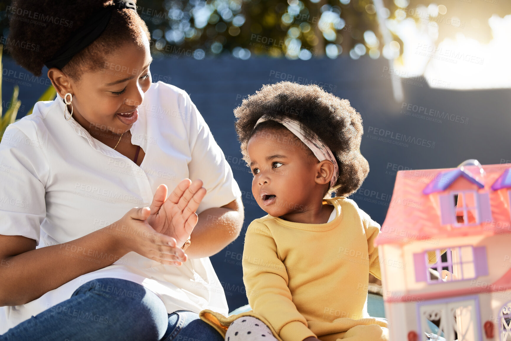 Buy stock photo Mother, baby and playing with toy in garden of home with doll house, fantasy and clapping hands with game. Black people, mom and daughter in backyard outdoor with bonding, support and imagination