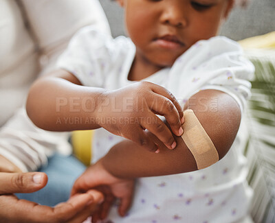 Buy stock photo Shot of a little girl applying a plaster to her arm at home