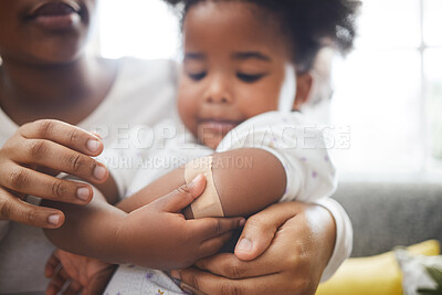 Buy stock photo Shot of an unrecognizable mother applying a bandaid to her daughter's arm at home
