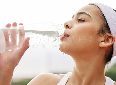 Buy stock photo Shot of a beautiful young woman drinking a bottle of water while out playing tennis