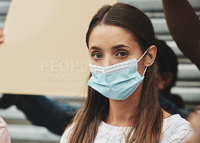 Buy stock photo Cropped portrait of an attractive young woman wearing a mask while taking part in a political rally