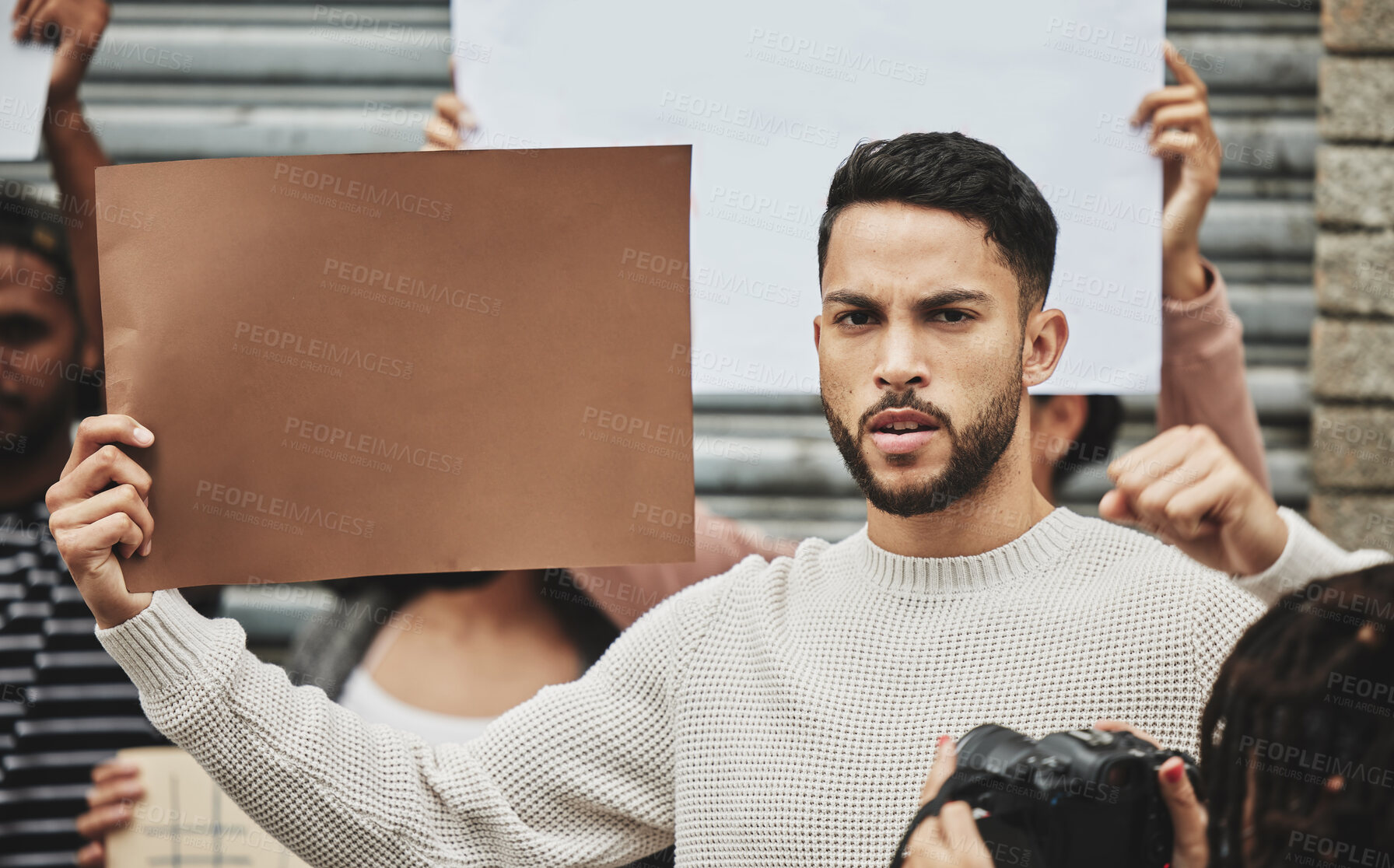 Buy stock photo Cropped portrait of a handsome young man holding a sign while taking part in a political rally