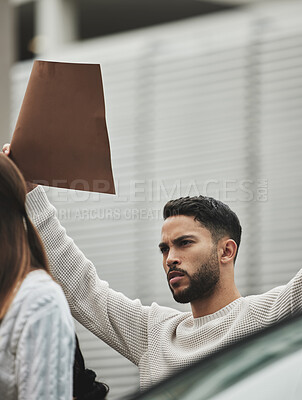 Buy stock photo Low angle shot of a handsome young man holding a sign while taking part in a political rally