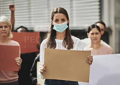 Buy stock photo Cropped portrait of an attractive young woman wearing a mask while taking part in a political rally