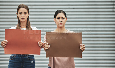 Buy stock photo Cropped portrait of two attractive young women holding signs while taking part in a political rally