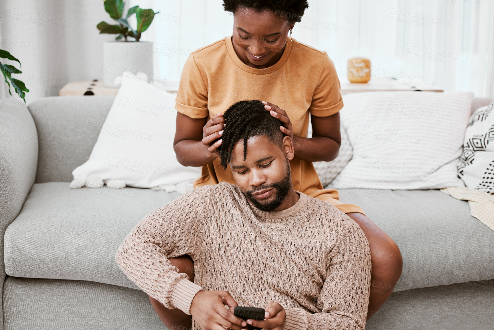 Buy stock photo Couple, black woman and man in living room, phone and together for love, smile and romance in home to relax. House, African person and partner in lounge, touch and happy for marriage and commitment