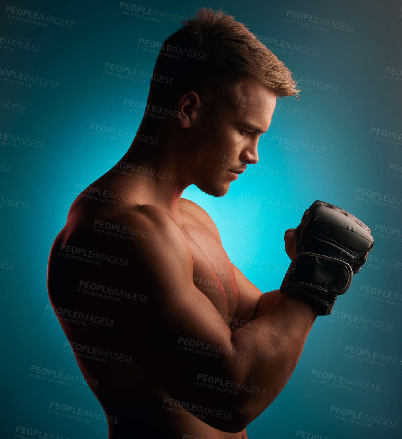 Buy stock photo Shot of a handsome young boxer standing alone and posing against a blue background in the studio