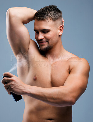 Buy stock photo Studio shot of a handsome young man applying deodorant against a grey background