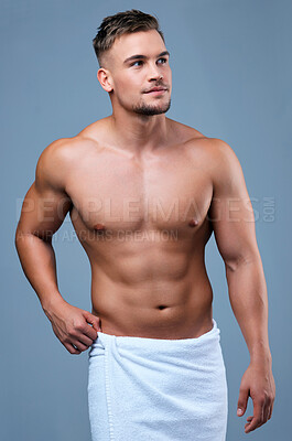 Buy stock photo Studio shot of a muscular young man posing in a towel against a grey background