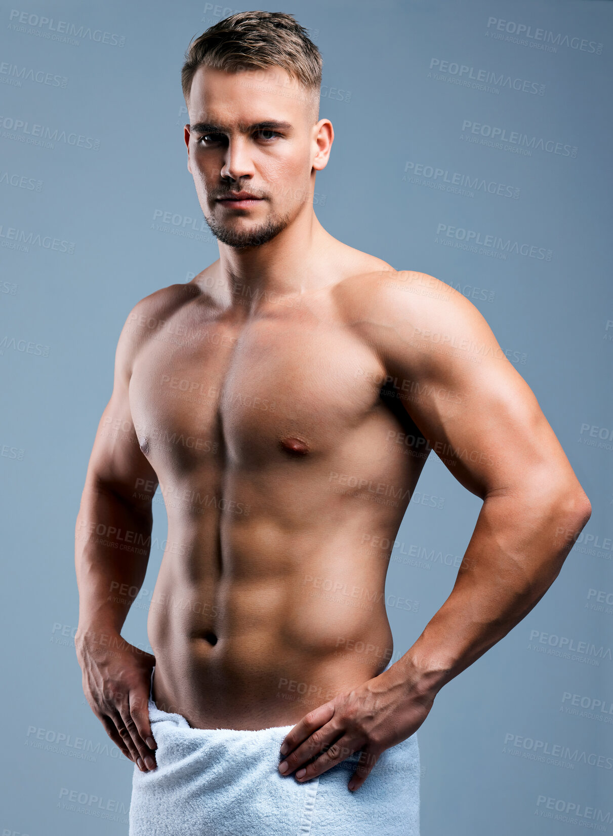 Buy stock photo Studio portrait of a muscular young man posing in a towel against a grey background